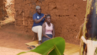 Image of two ugandan girls, one braiding the others hair